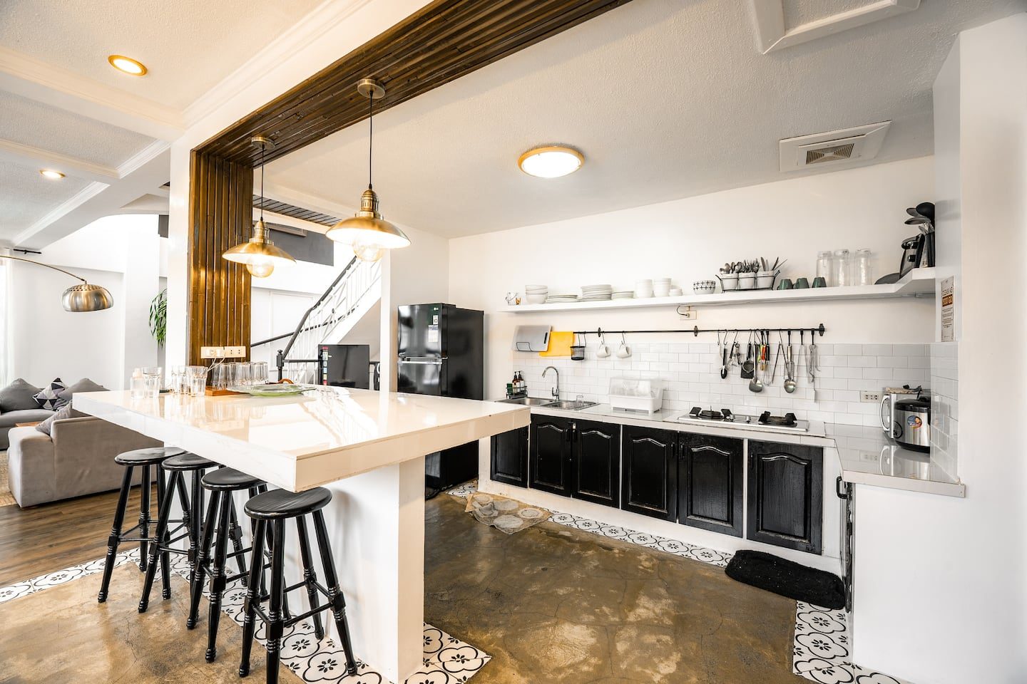 The white kitchen island with black bar stools and pendant lights
