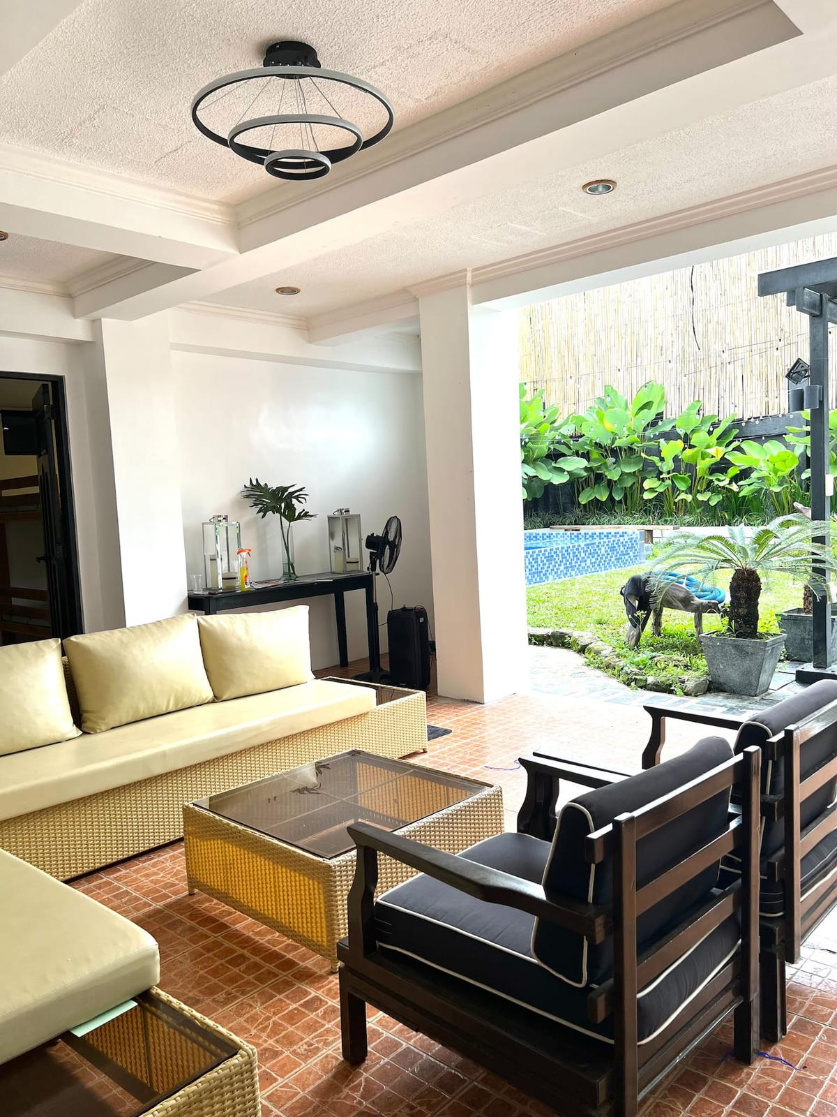 The covered lanai with a sofa set opening onto the garden and pool