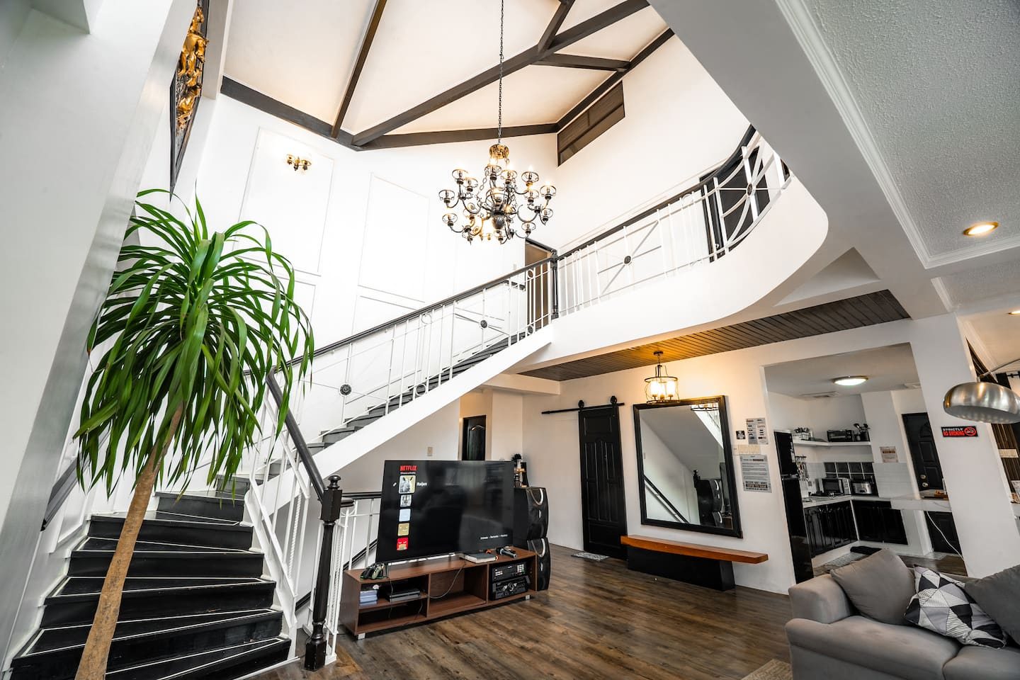The double-height living room: white walls, black stair rail, grey sofas around a wooden table